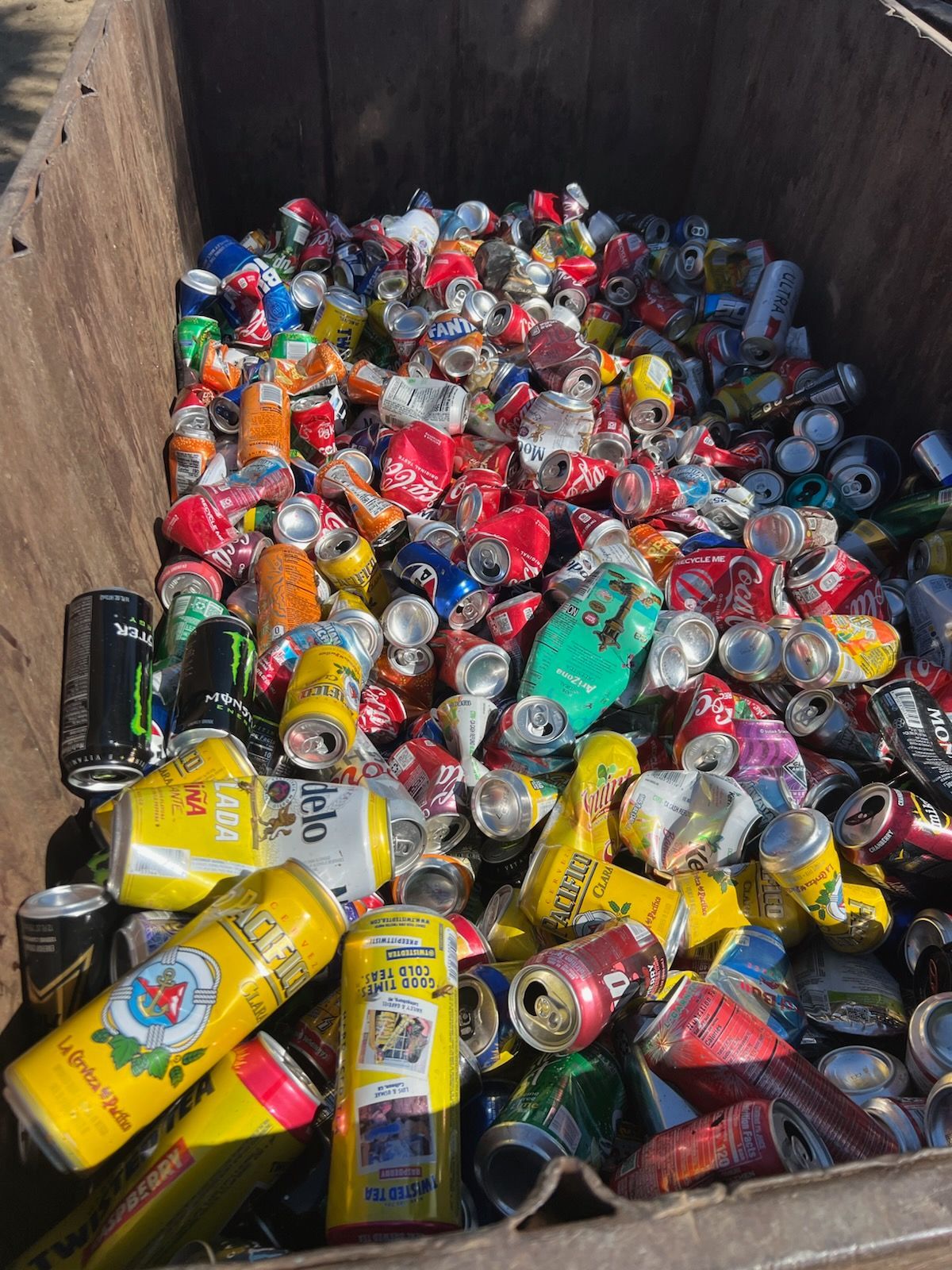 A pile of crushed aluminum cans in a dumpster.
