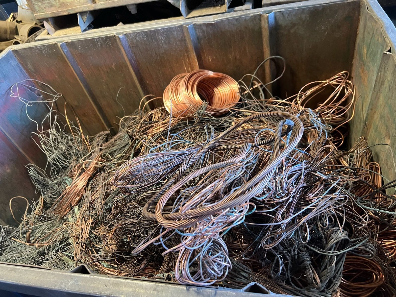 A wooden box filled with a pile of copper wire.