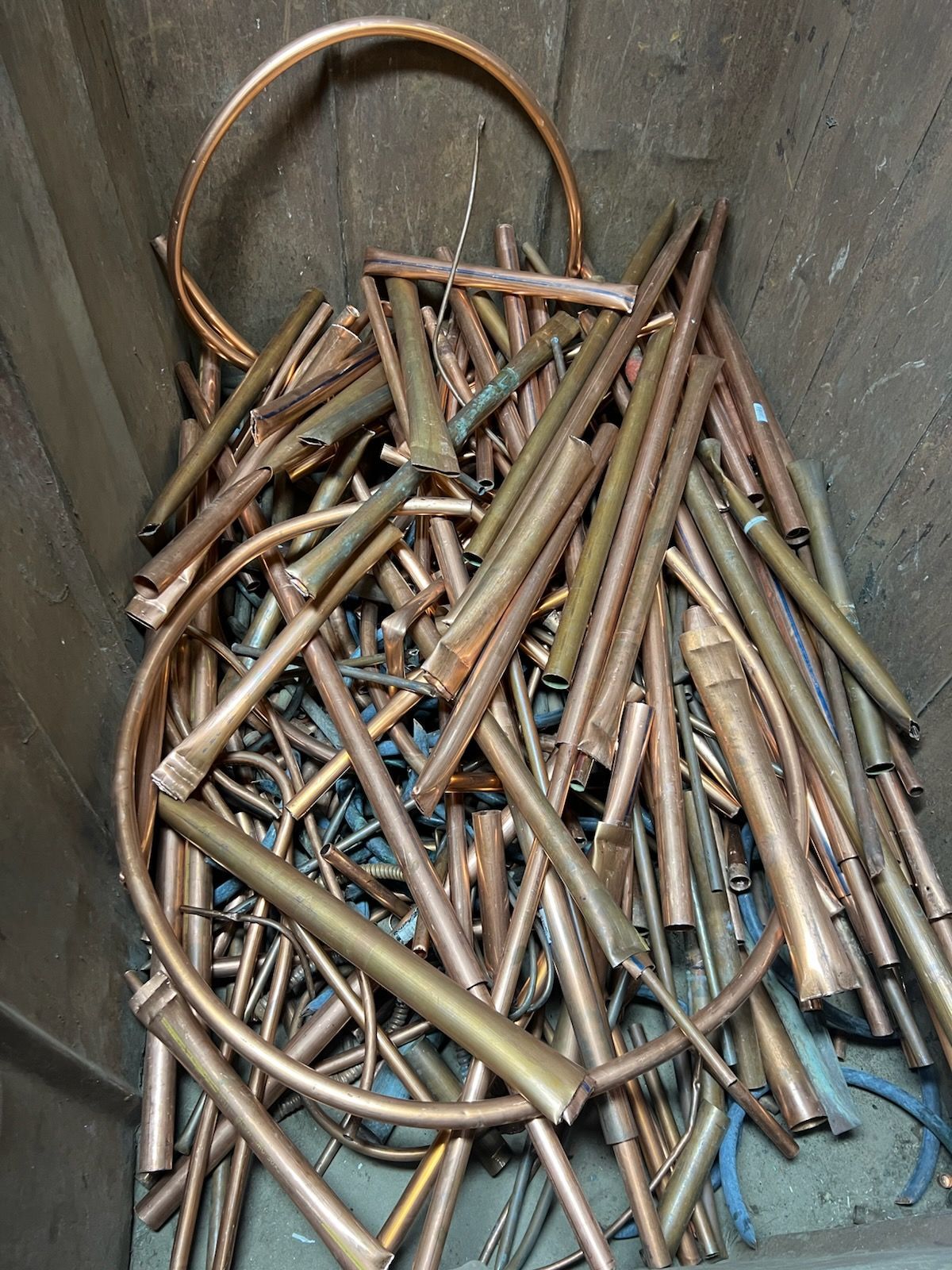 A pile of copper pipes and wires in a bin.