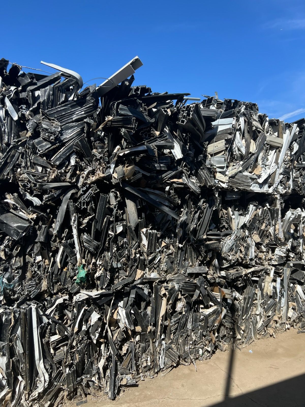 A large pile of scrap metal is sitting on top of a dirt road.