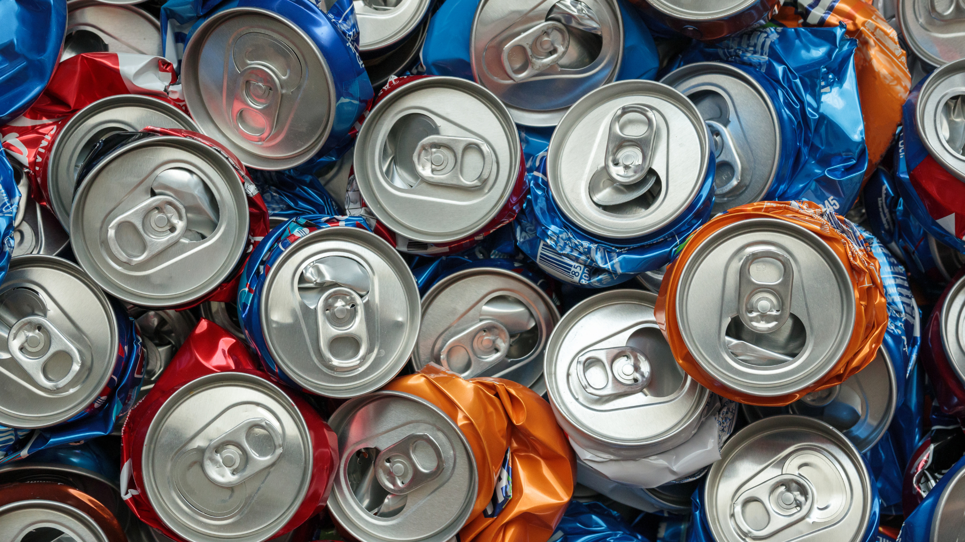A pile of crushed cans of soda are stacked on top of each other.