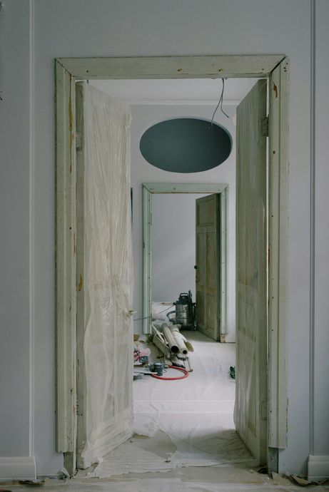 Open doorway into a hallway; construction debris on floor, more doorways in view.