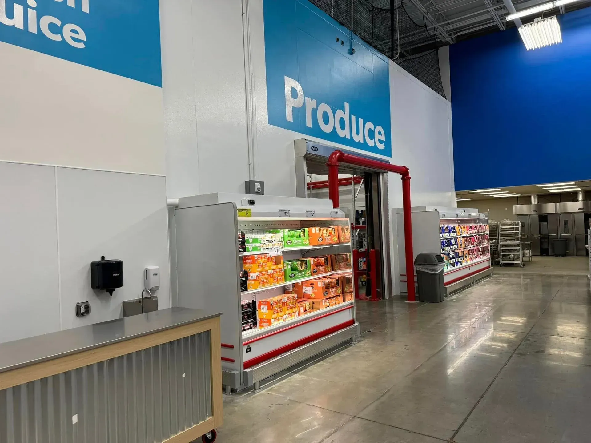 A produce section of a grocery store with a blue sign on the wall.