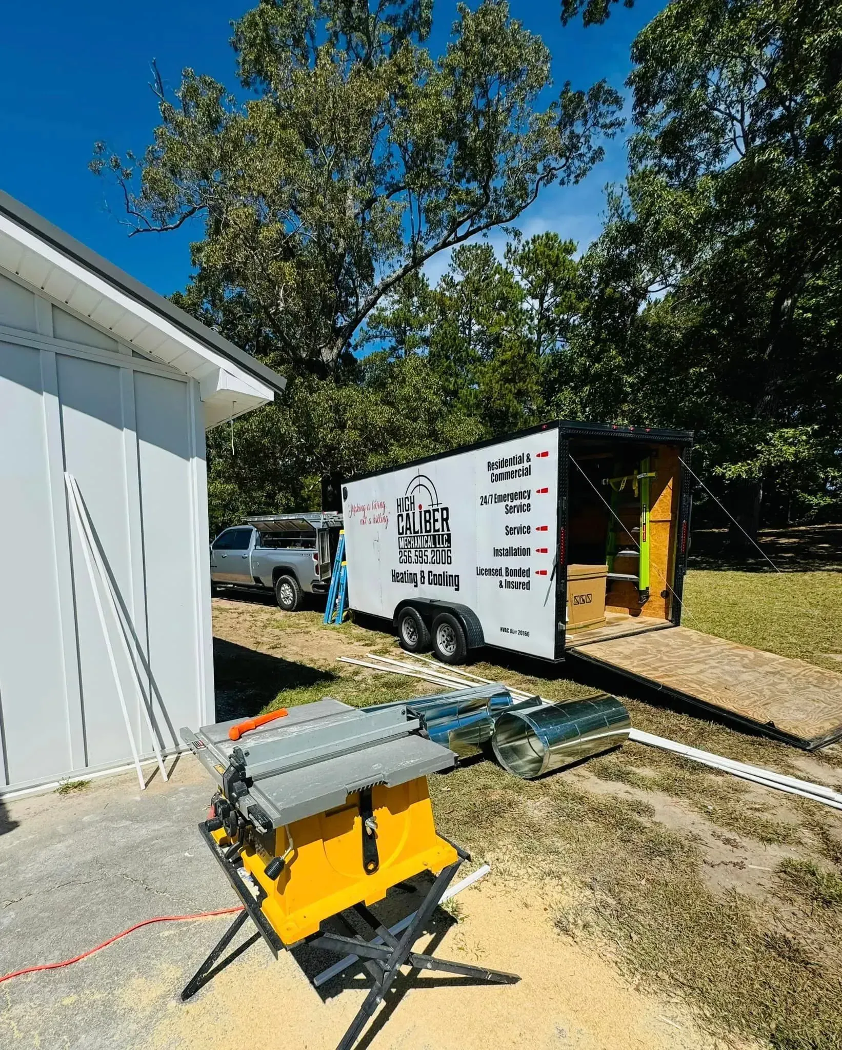 A table saw is sitting in front of a trailer.