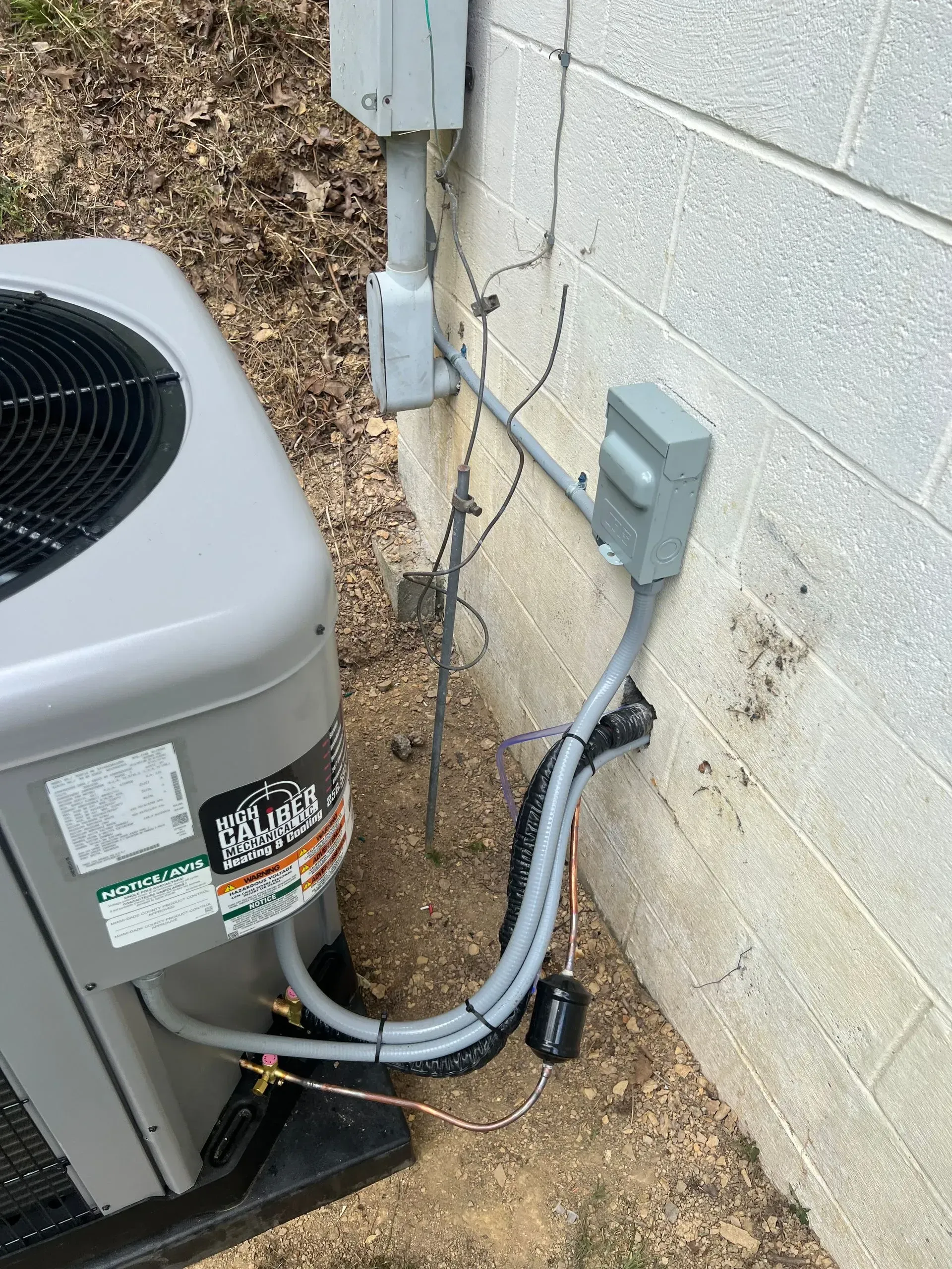 A gray air conditioner is attached to a brick wall.