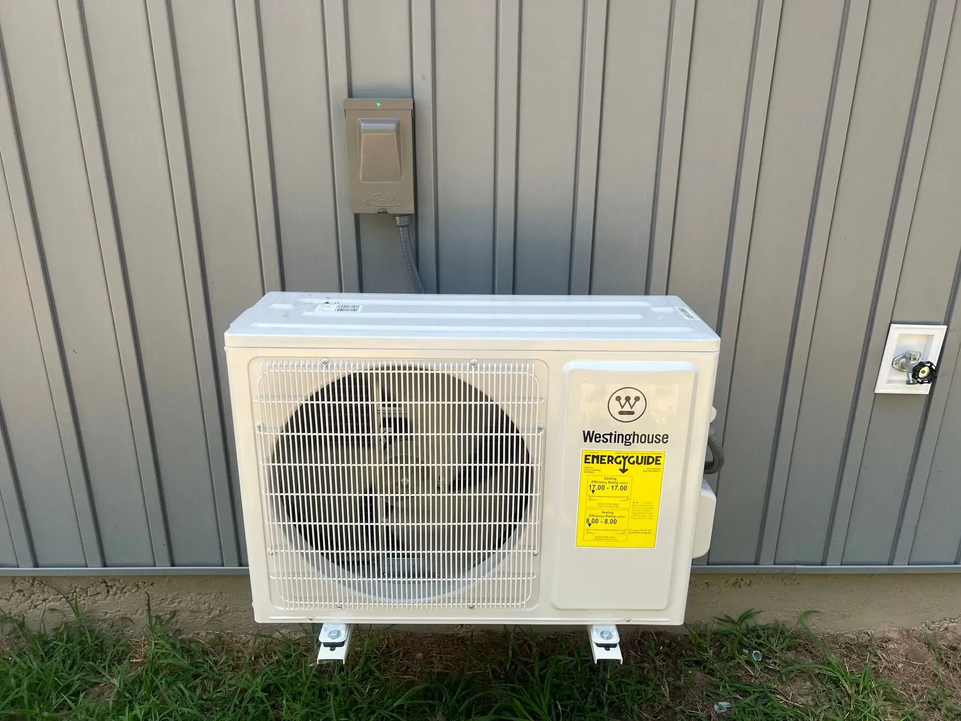 A white air conditioner is mounted on the side of a building.