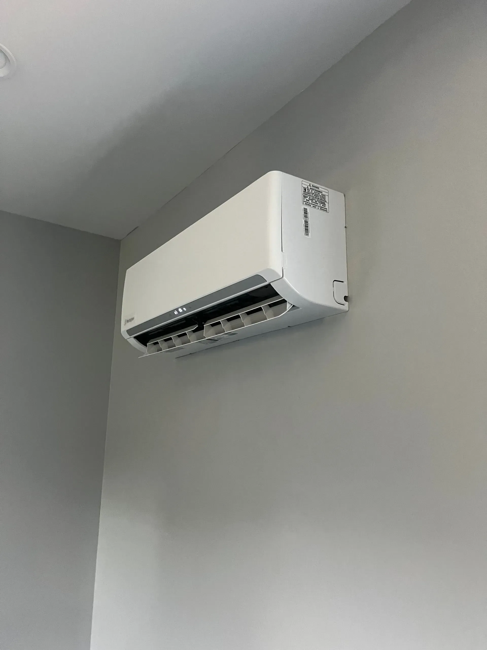 A white air conditioner is hanging on a wall in a room.