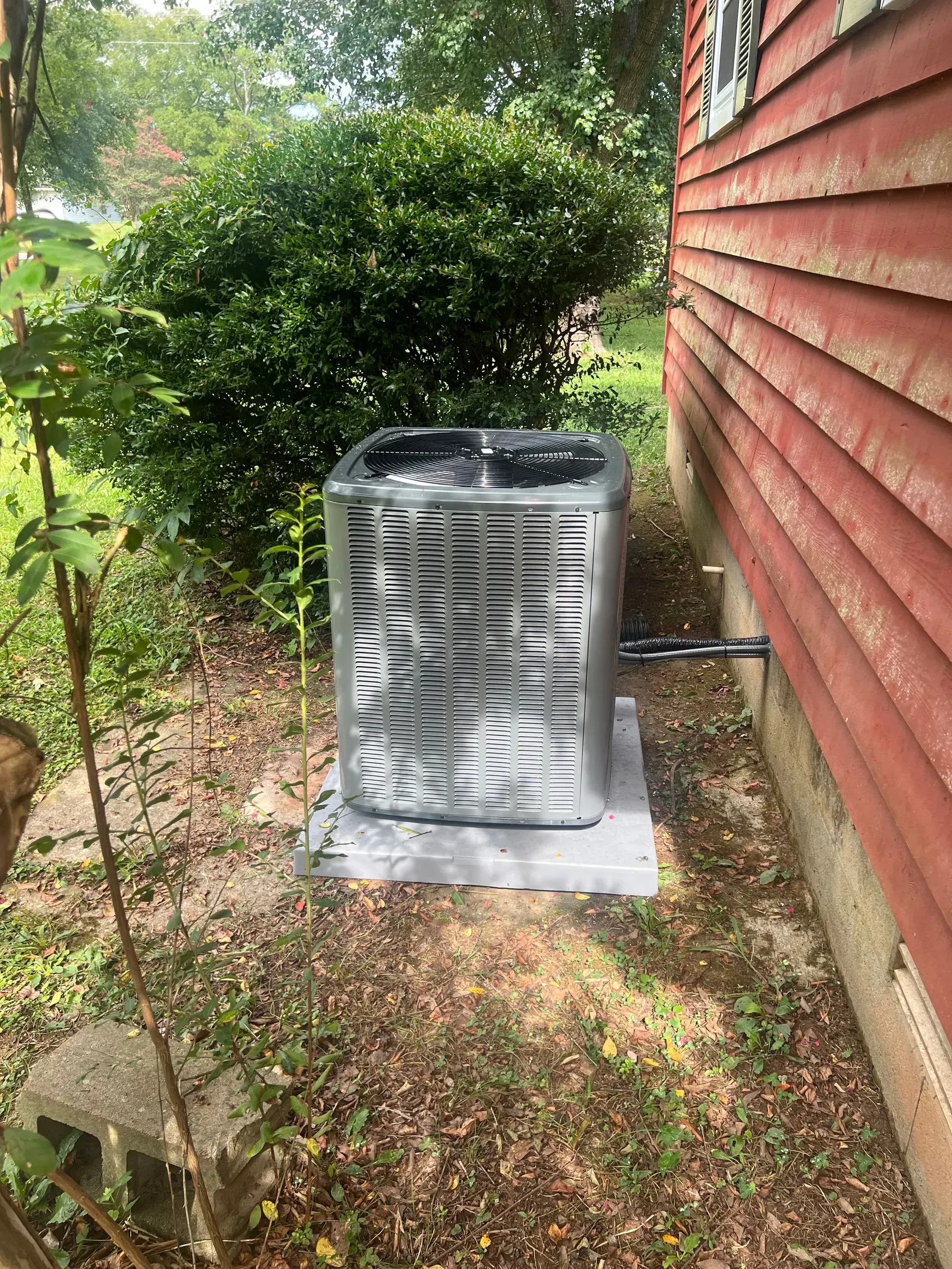 An air conditioner is sitting on the side of a house.