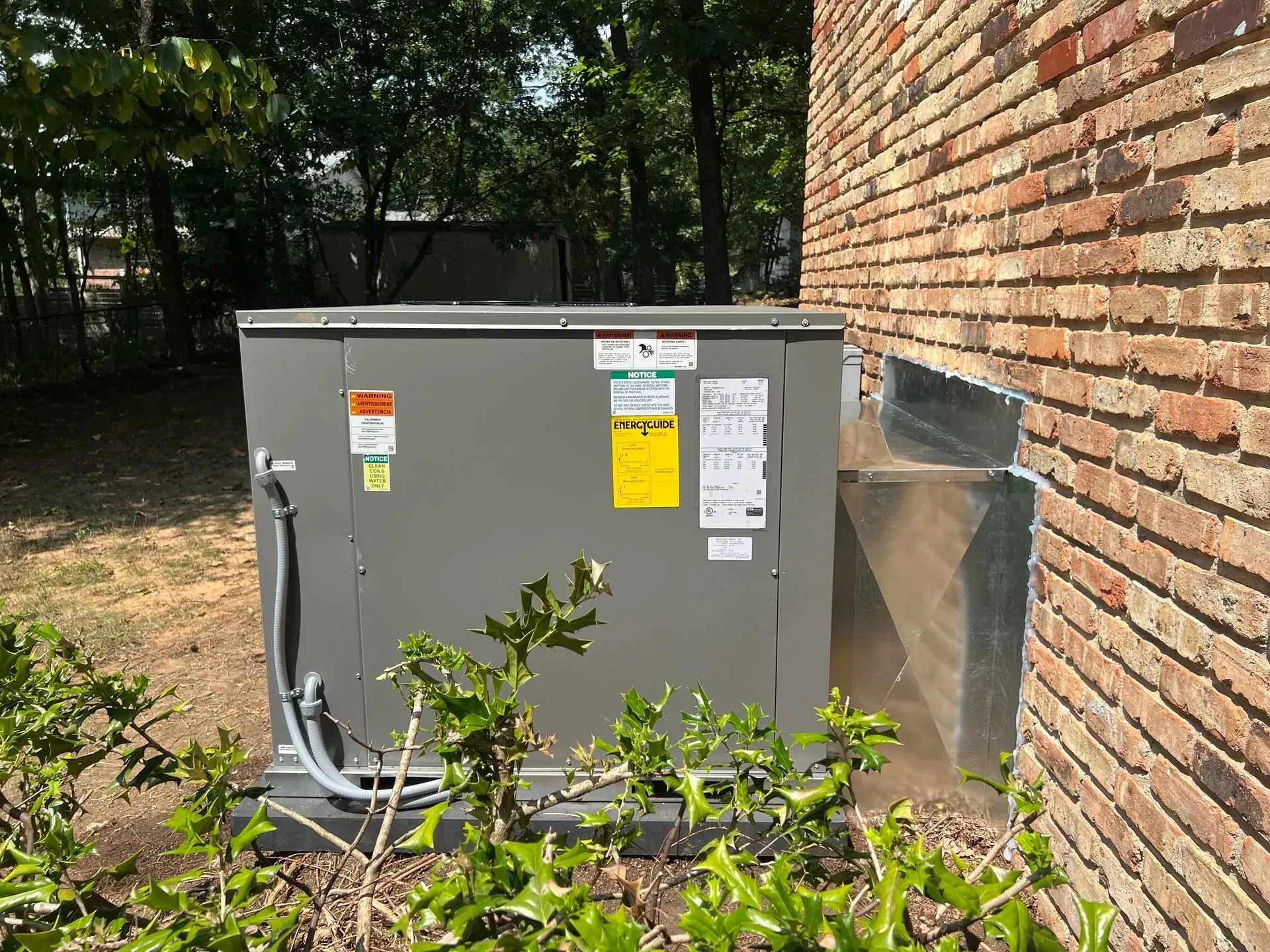 A large box is sitting on the side of a brick building.
