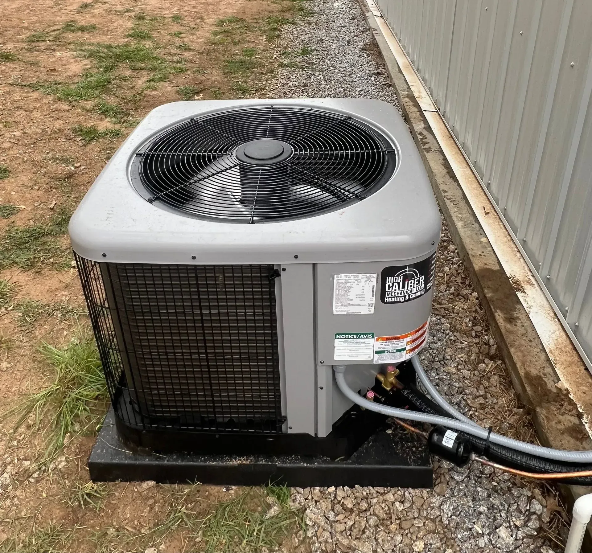 A large air conditioner is sitting on the ground next to a building.