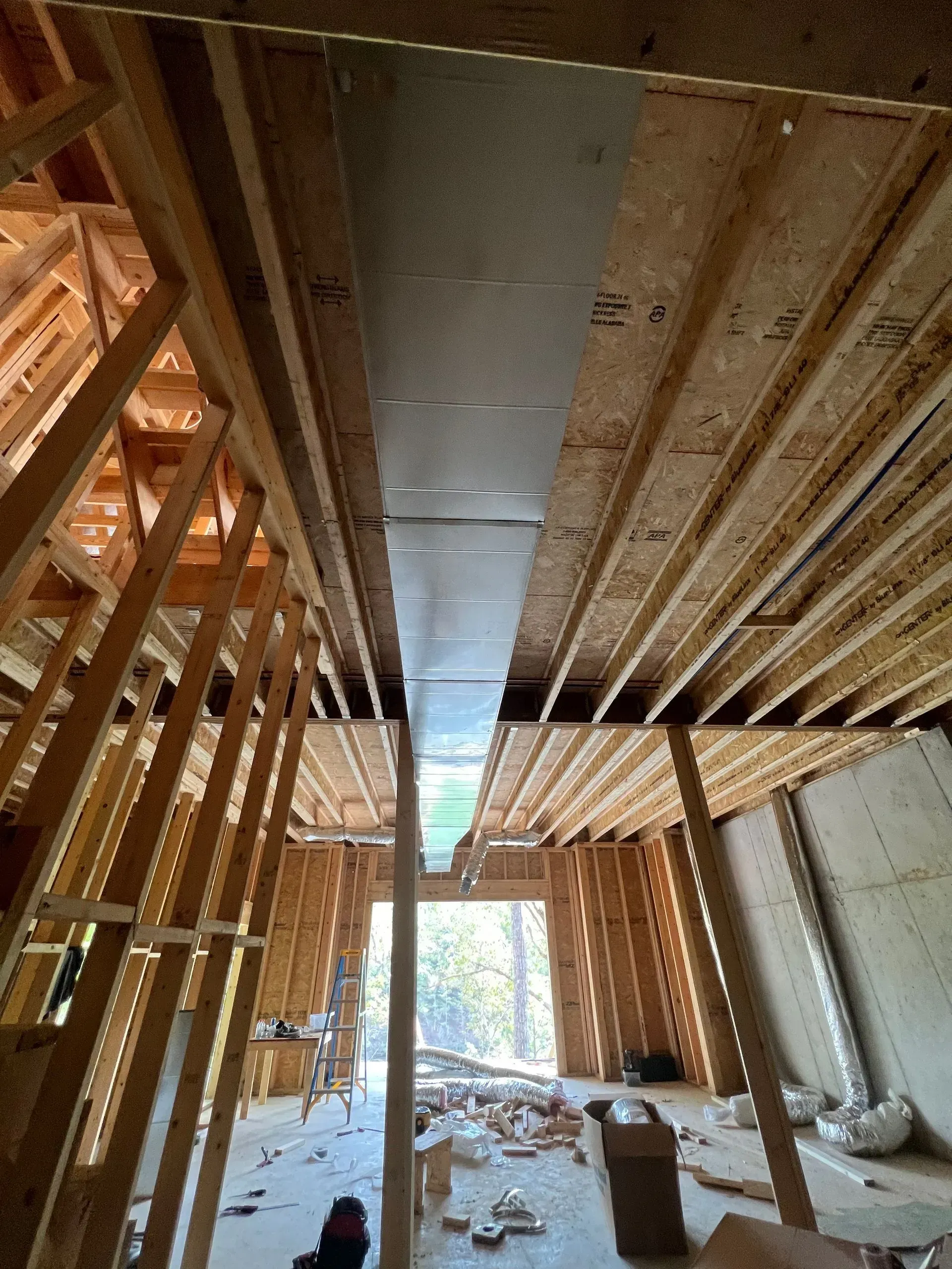 A house is being built with wooden beams and a metal pipe coming out of the ceiling.