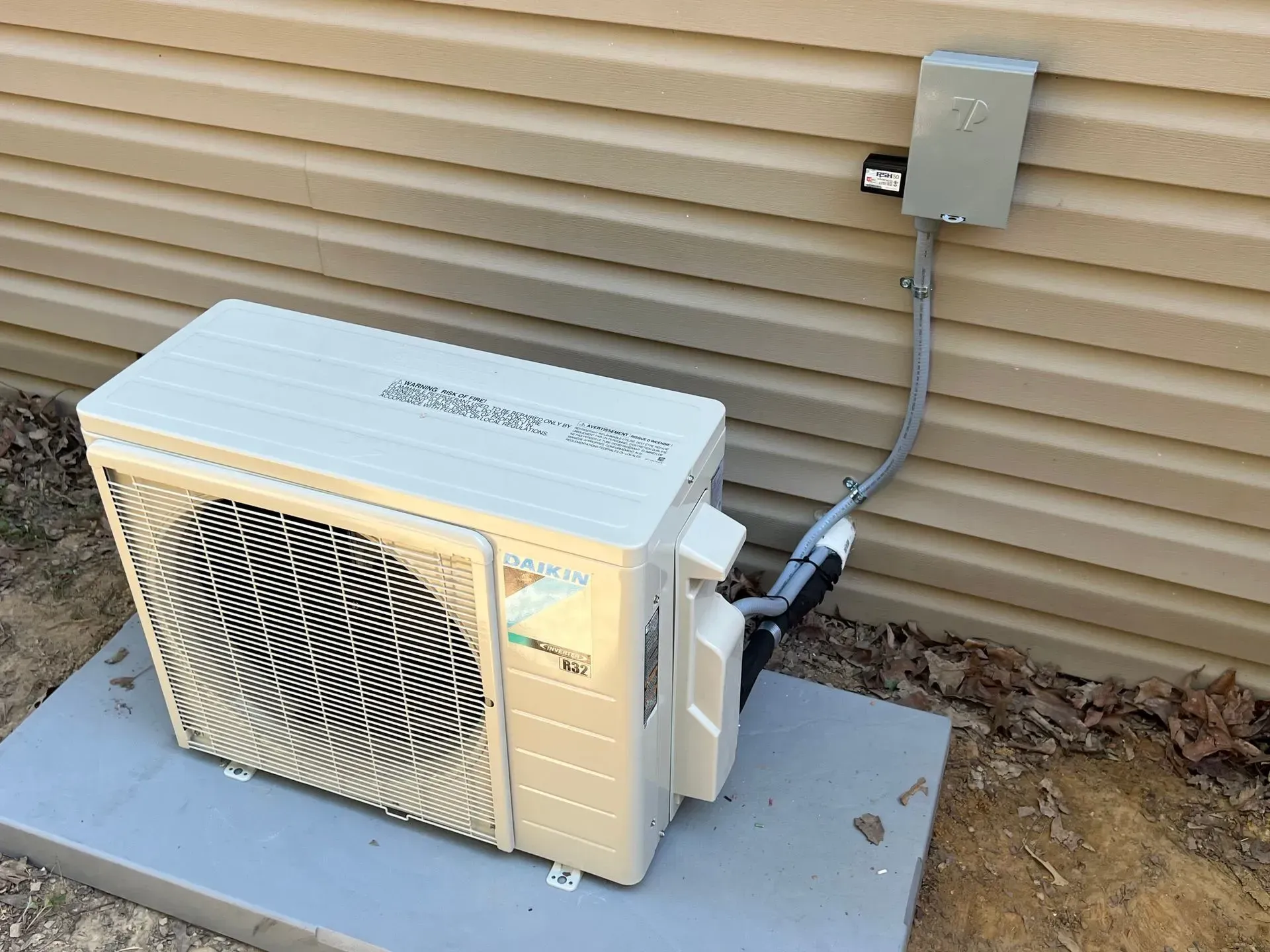 A white air conditioner is attached to the side of a house.