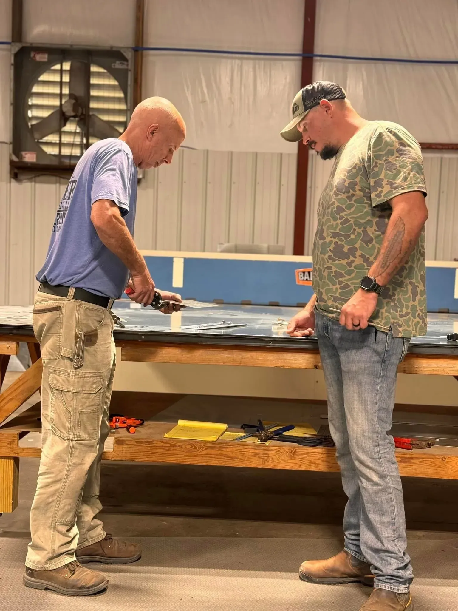 Two men are standing next to each other in a room looking at something.