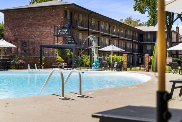 A large swimming pool in front of a large apartment building.