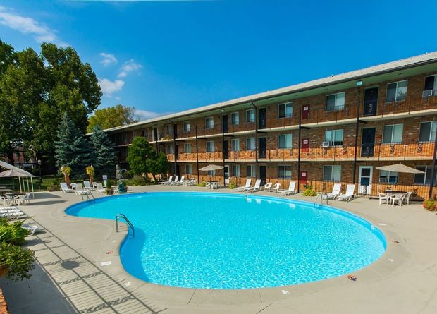 A large swimming pool in front of a large apartment building.