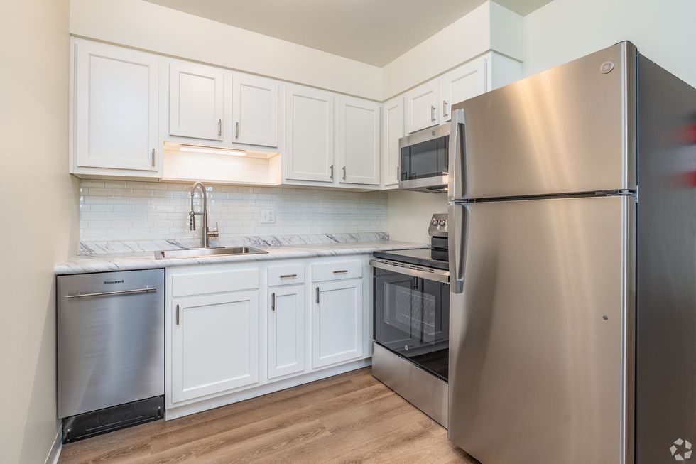 A kitchen with black cabinets , a white refrigerator , a stove , and a sink.