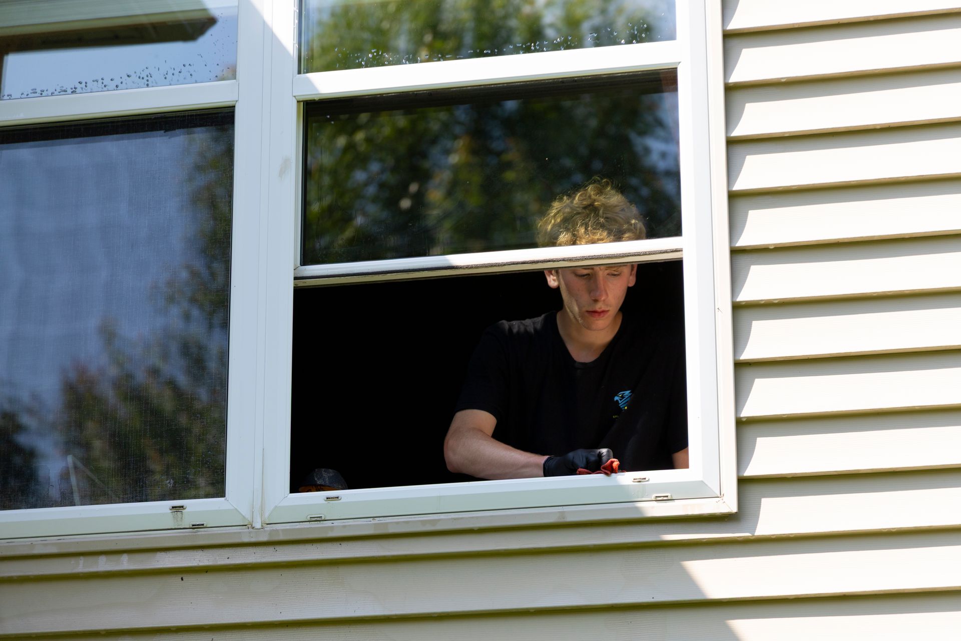 A man is looking out of a window with a drill.