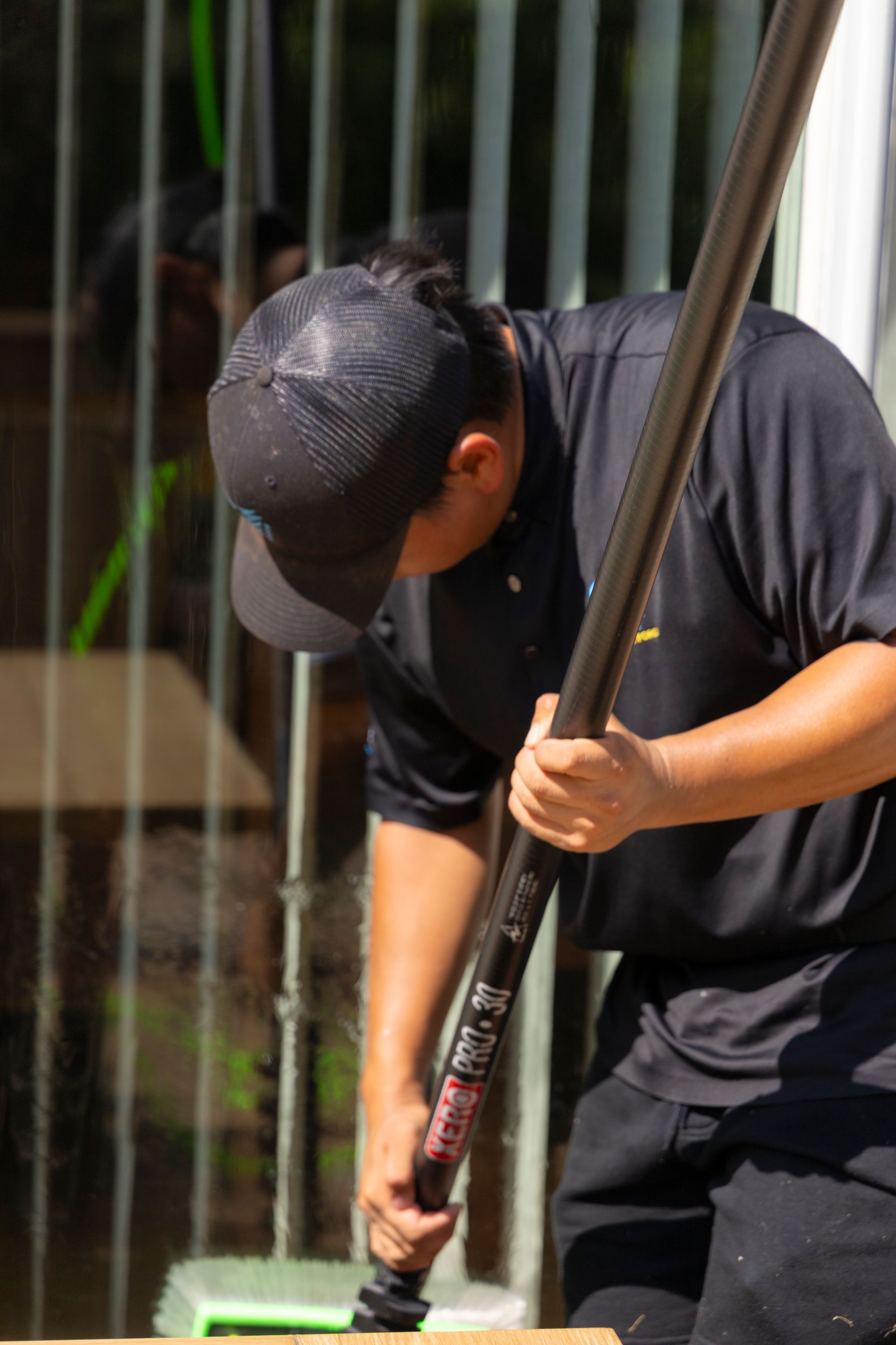 A man is cleaning a window with a mop.