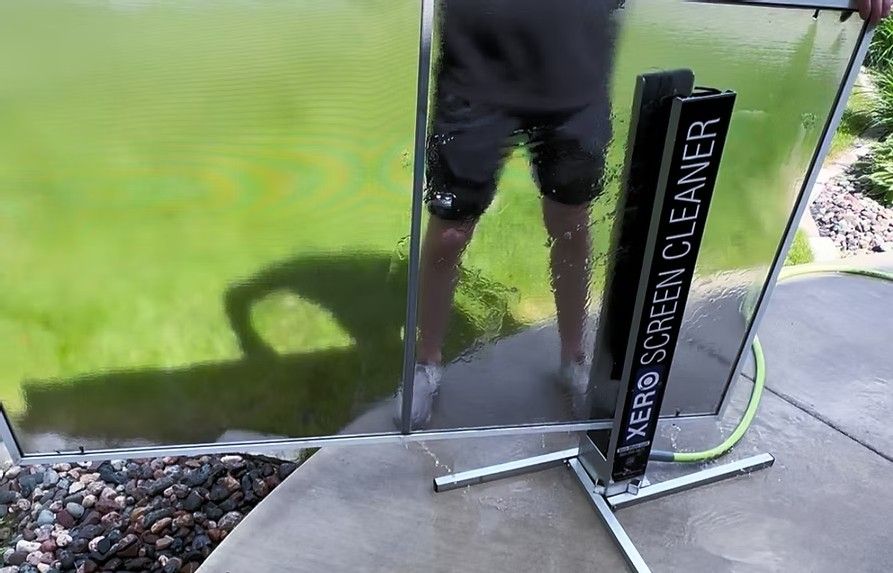 A man is standing next to a screen cleaner in front of a pond.