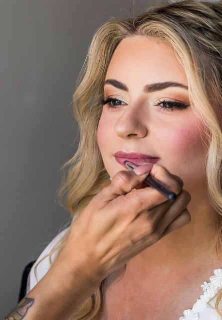 A woman is getting her makeup done by a makeup artist.