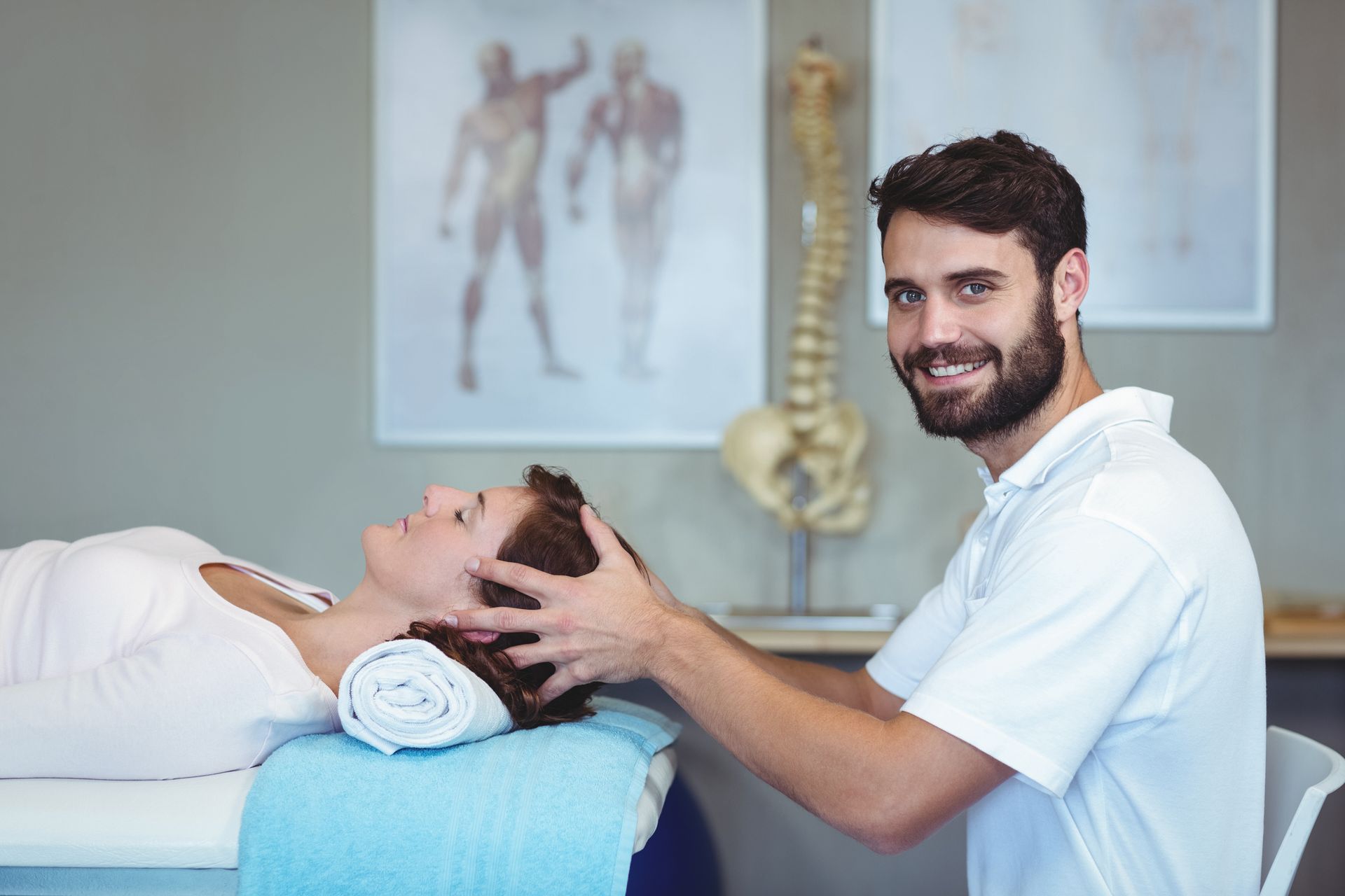 A male physiotherapist giving a head massage to a female patient.