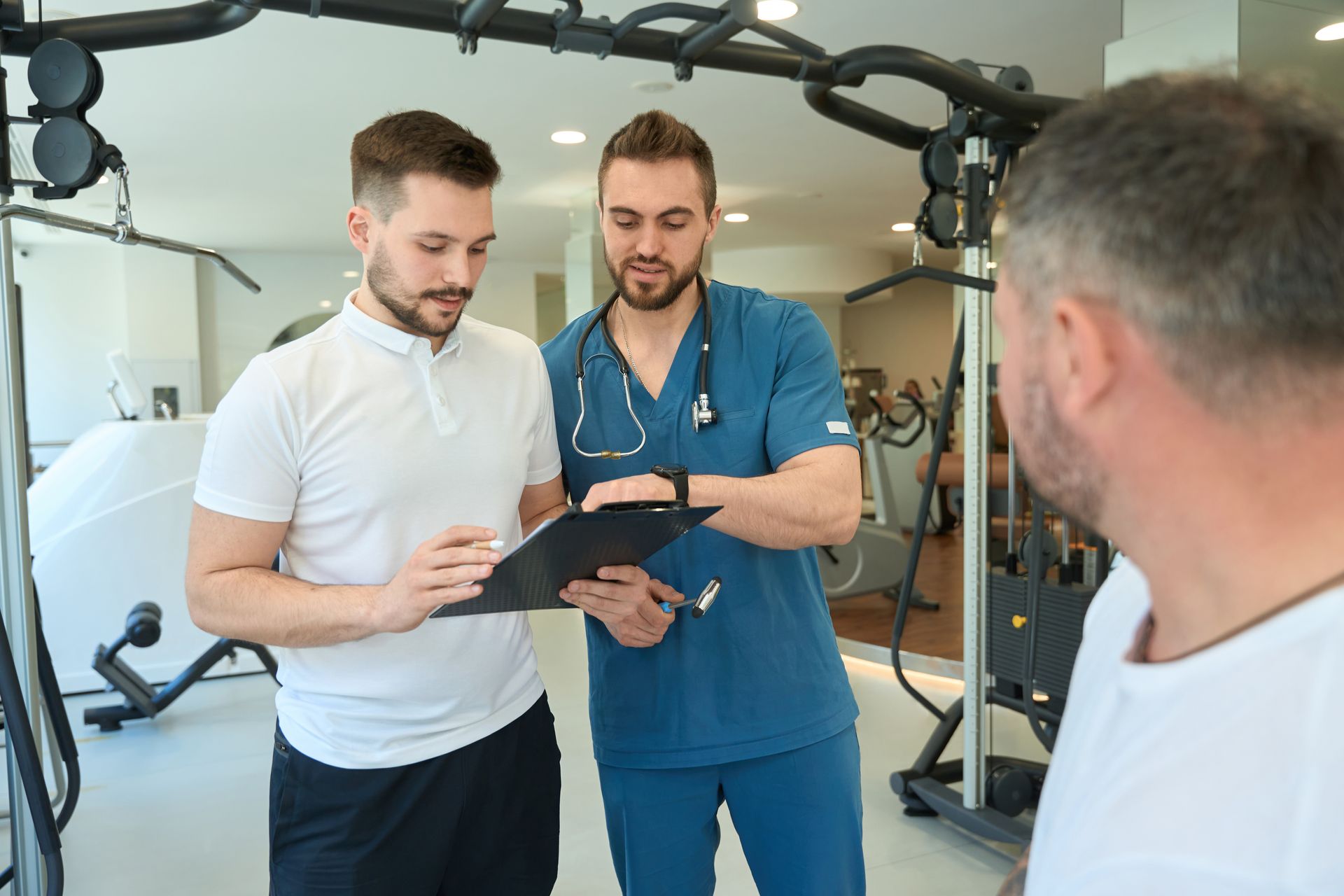 Physiotherapist and gym trainer discussing exercise program for a patient.
