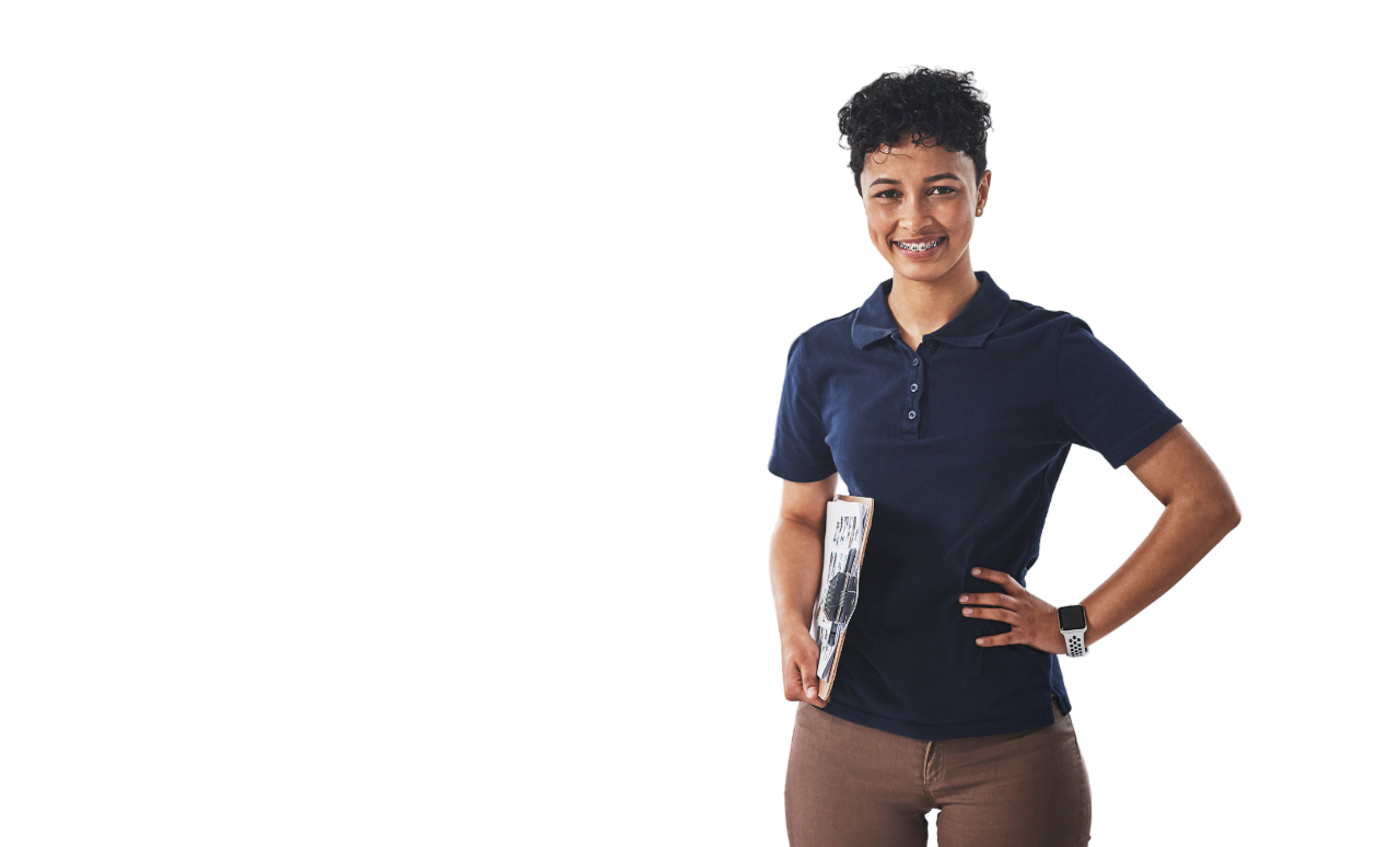 Smiling woman with short dark hair in a navy polo and brown pants holds a clipboard, standing confidently with hand on hip.