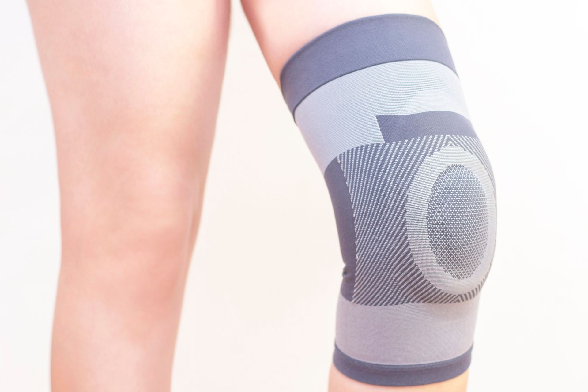 Knee brace on a person's leg, grey and black in color, providing support to the knee.