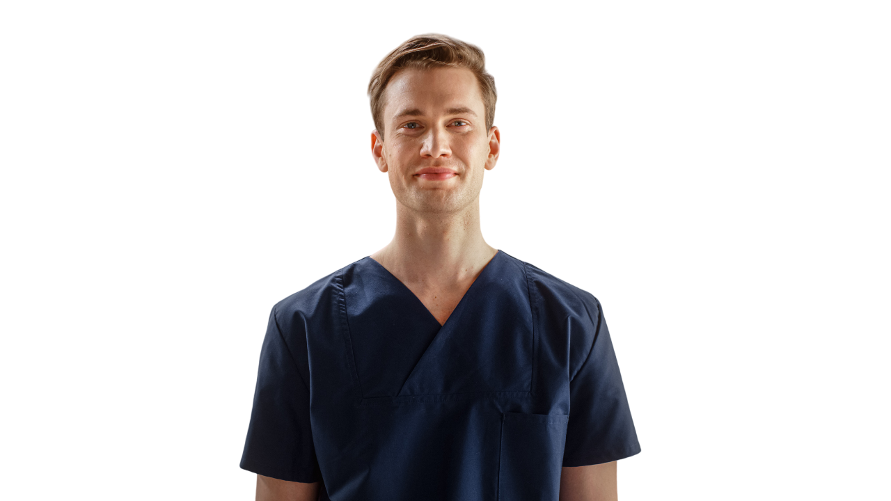 Man with light skin in navy blue scrubs, smiling in front of a white background.
