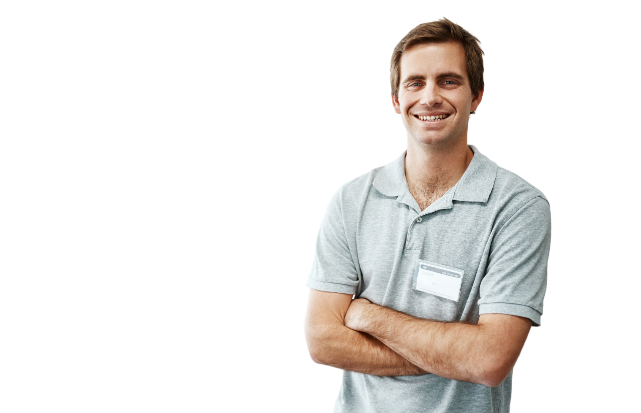 Man in gray polo shirt with arms crossed, smiling, wearing an ID badge, against a white background.