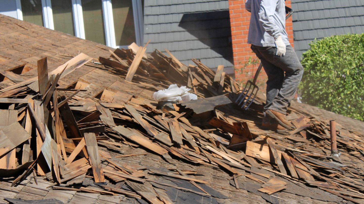 A man is standing on top of a pile of wood in roof