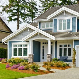 A blue and white house with a lush green lawn in front of it