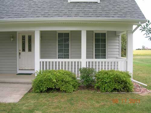 A house with a porch and bushes in front of it