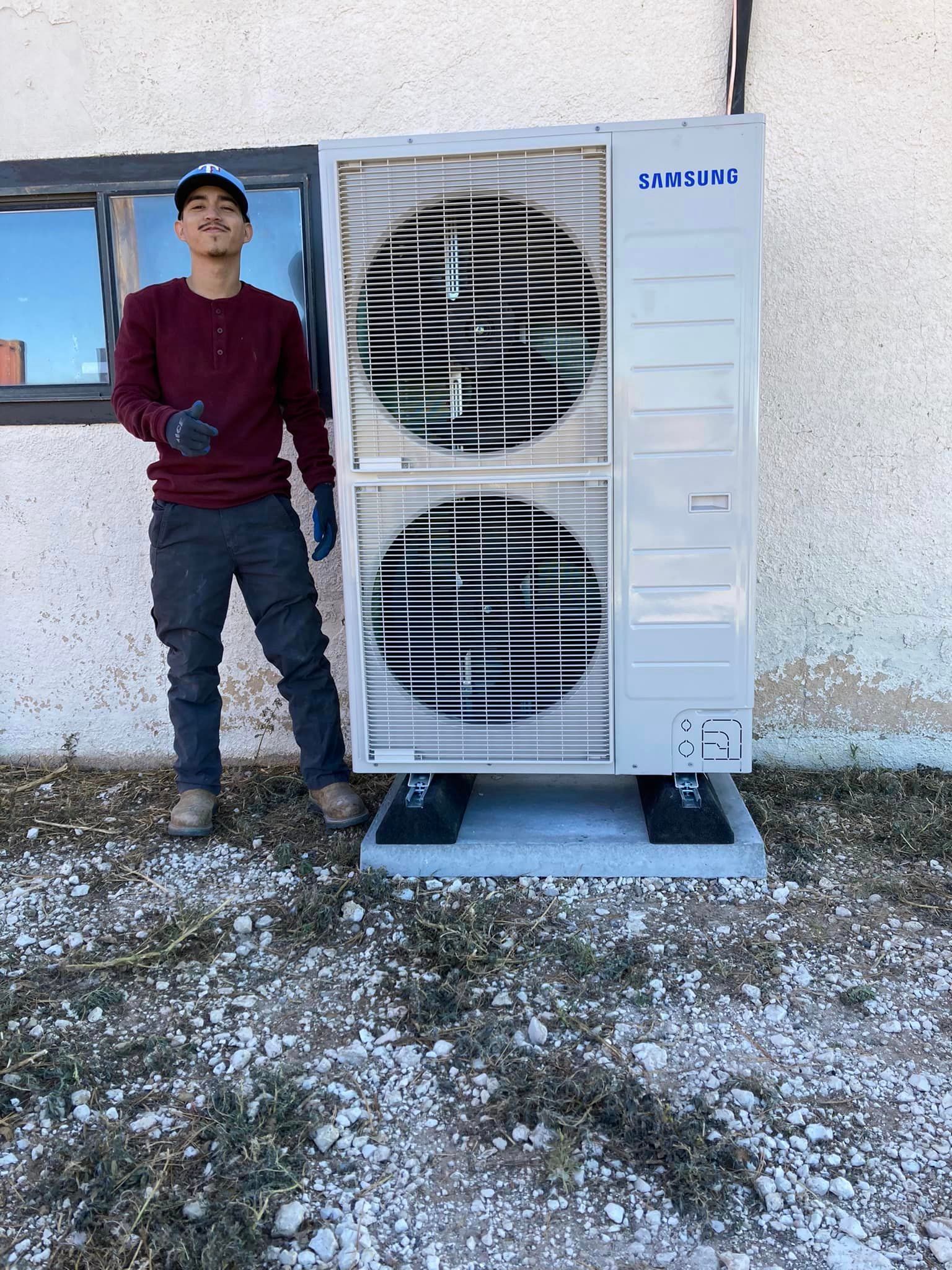 A man is standing next to a large air conditioner outside of a building.
