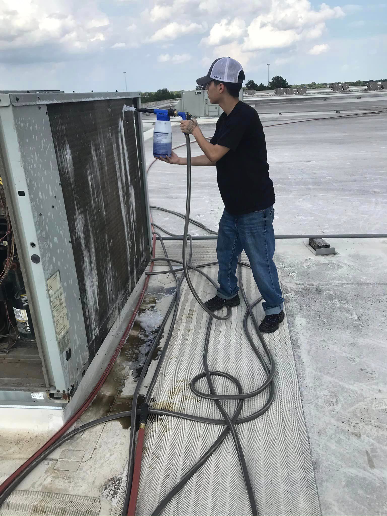 A man is cleaning a roof with a spray bottle.