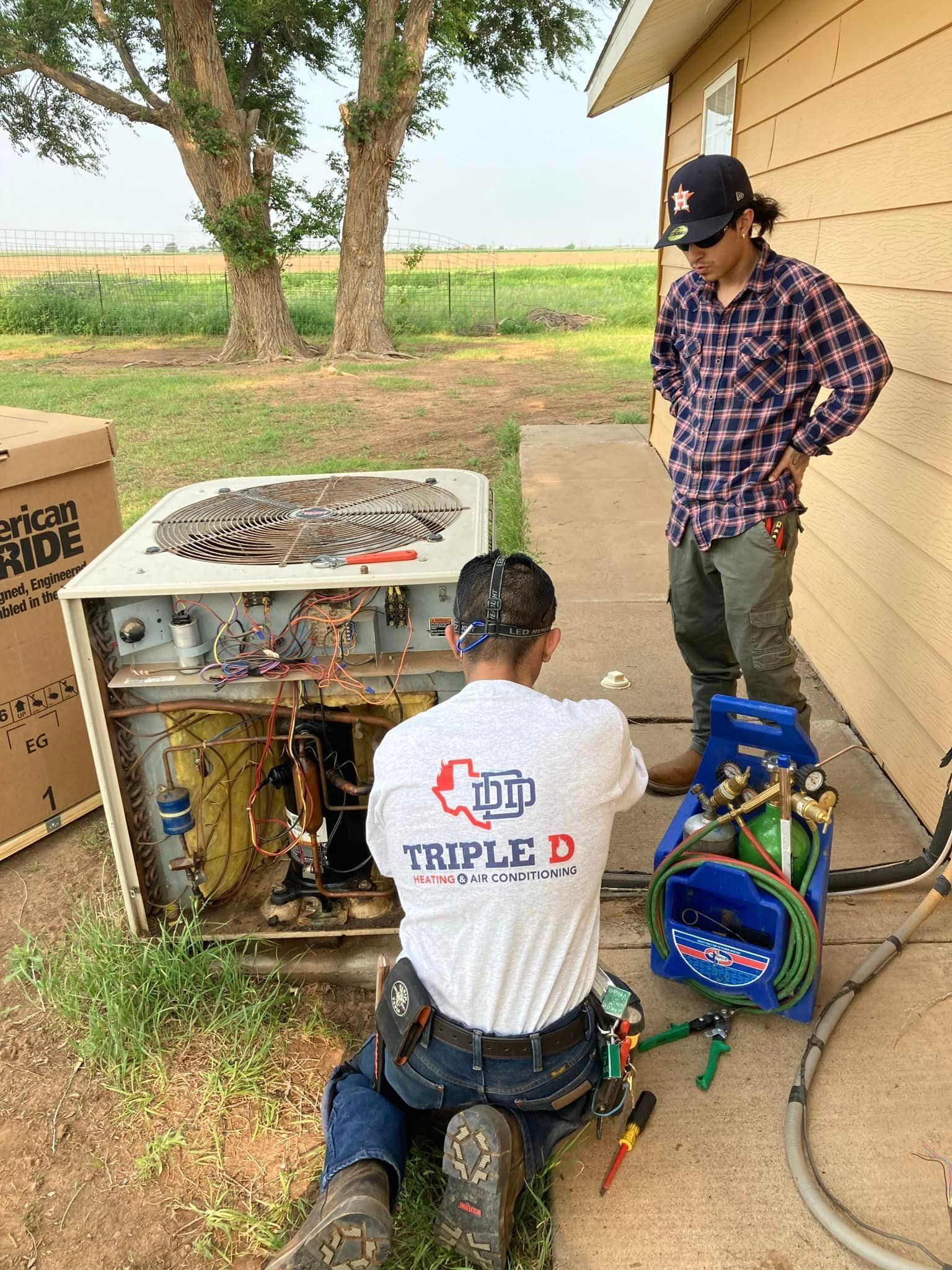 Two men are working on an air conditioner outside of a house.