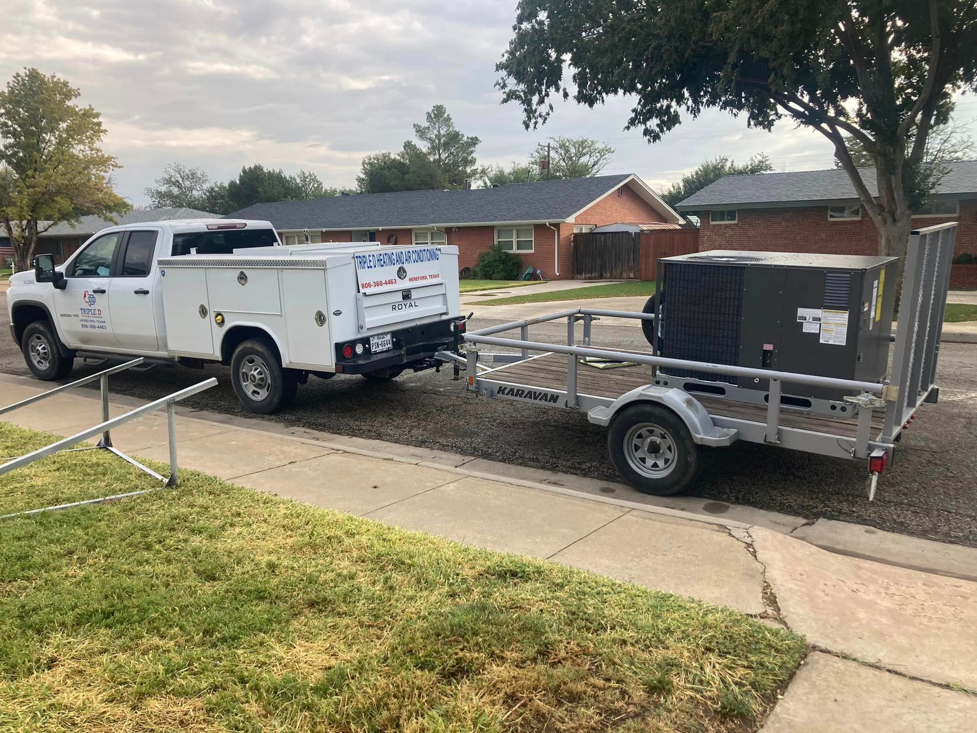 A white truck with a trailer attached to it is parked on the side of the road.