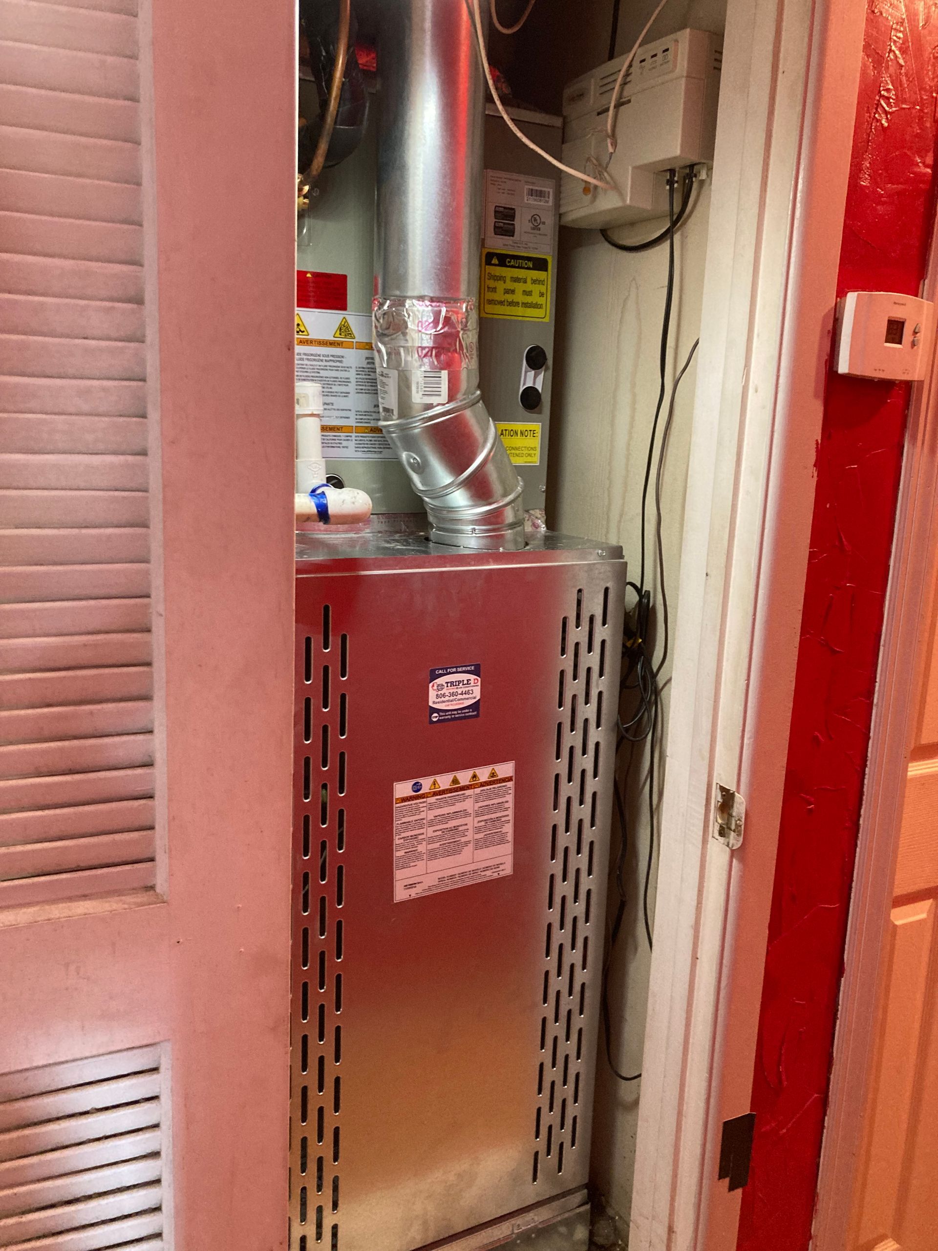 An air conditioner is sitting in a closet next to a door.