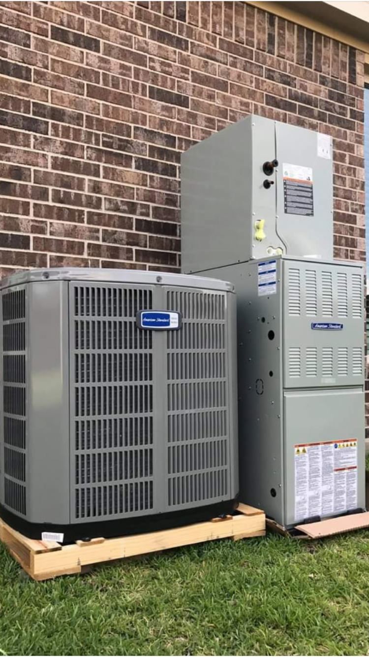 Two air conditioners are sitting next to each other on the side of a brick building.