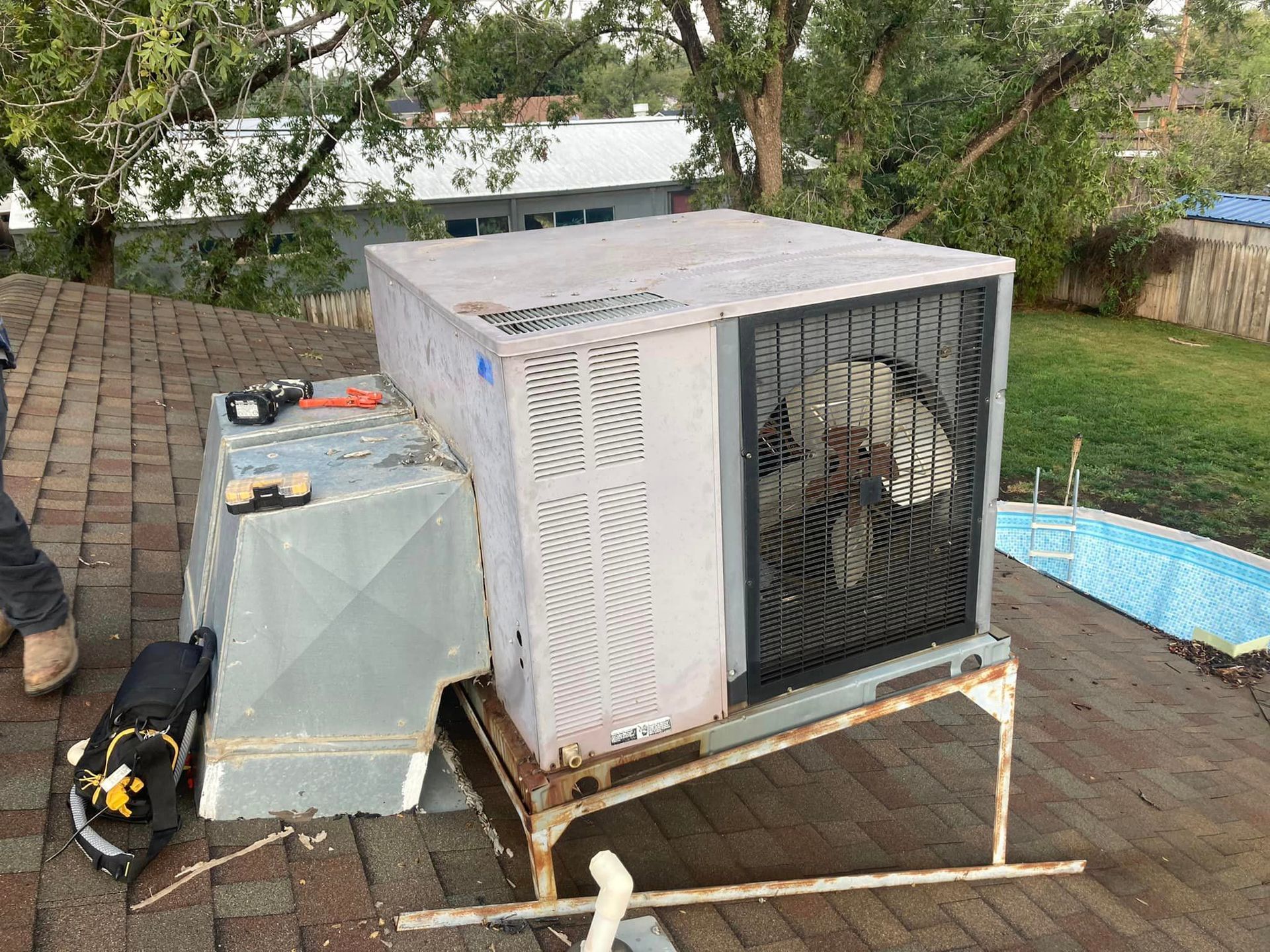 An air conditioner is sitting on top of a brick patio next to a pool.