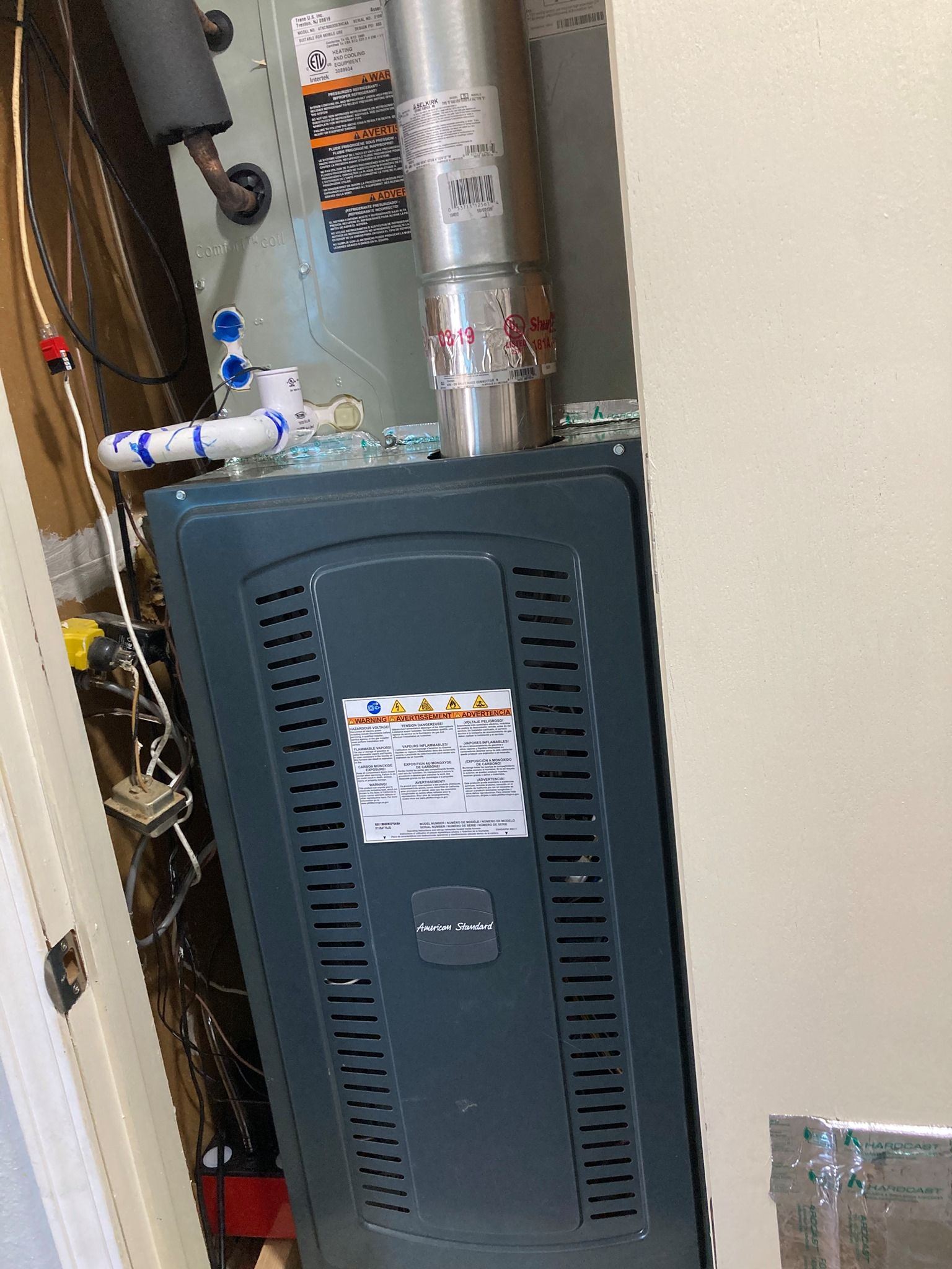 A gas heater is sitting in a closet next to a water heater.