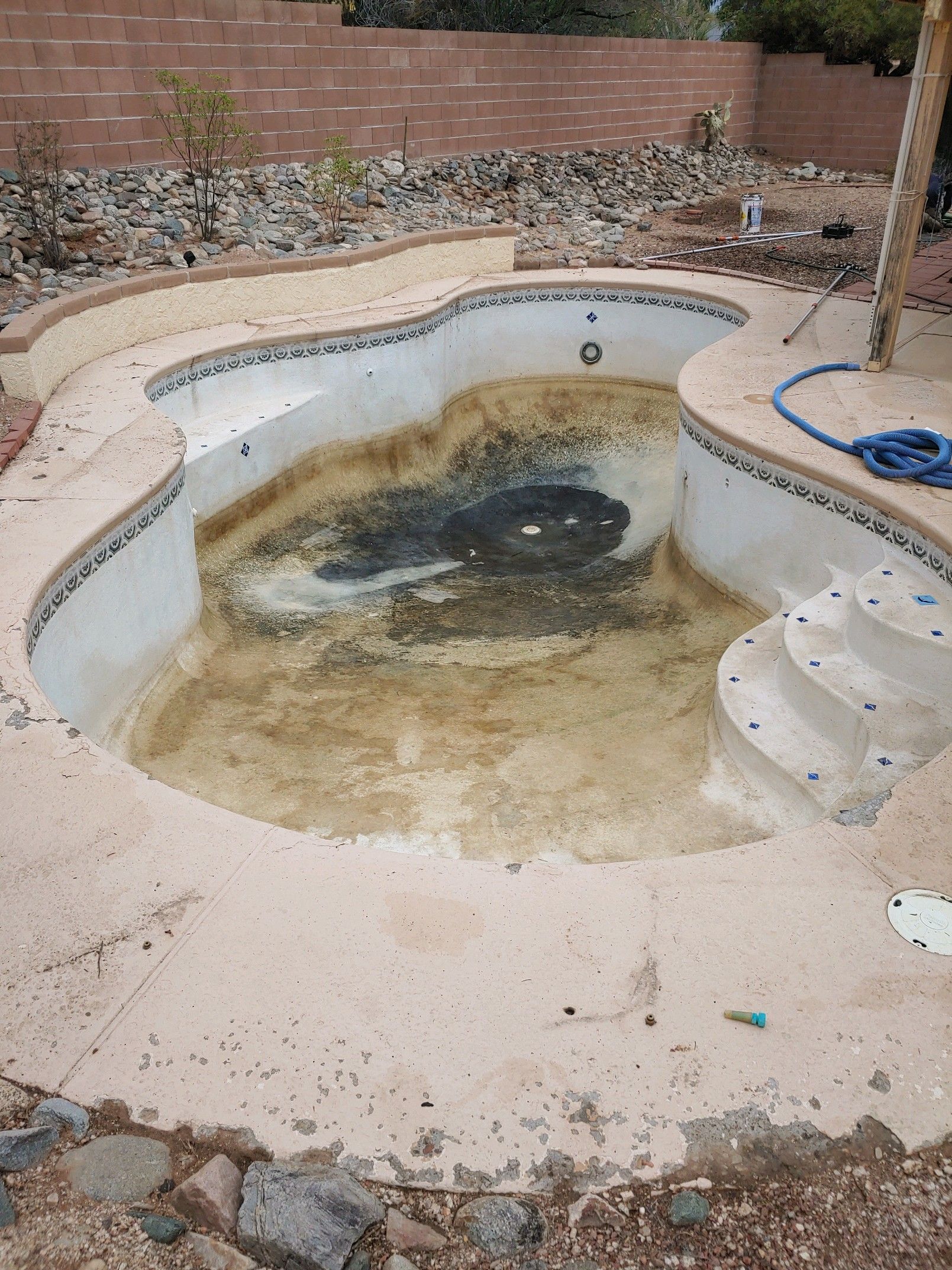 An empty swimming pool with a hose on the side of it.