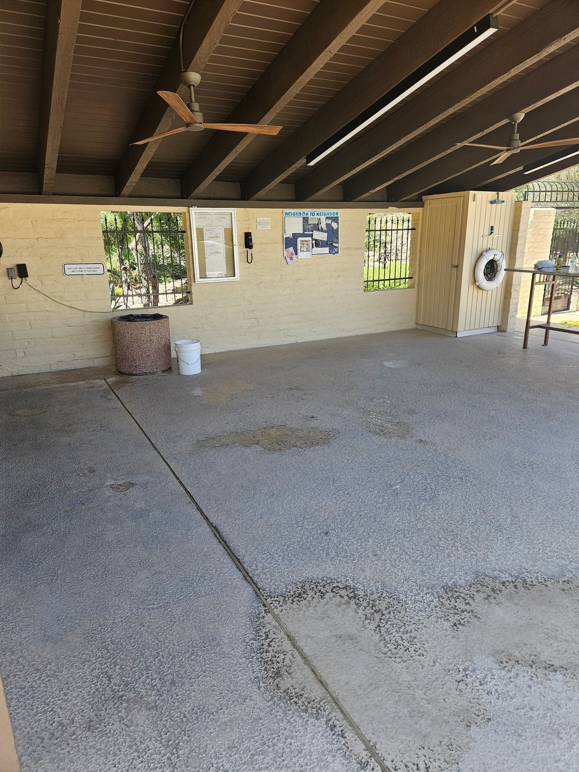 An empty room with a ceiling fan and a bucket on the floor