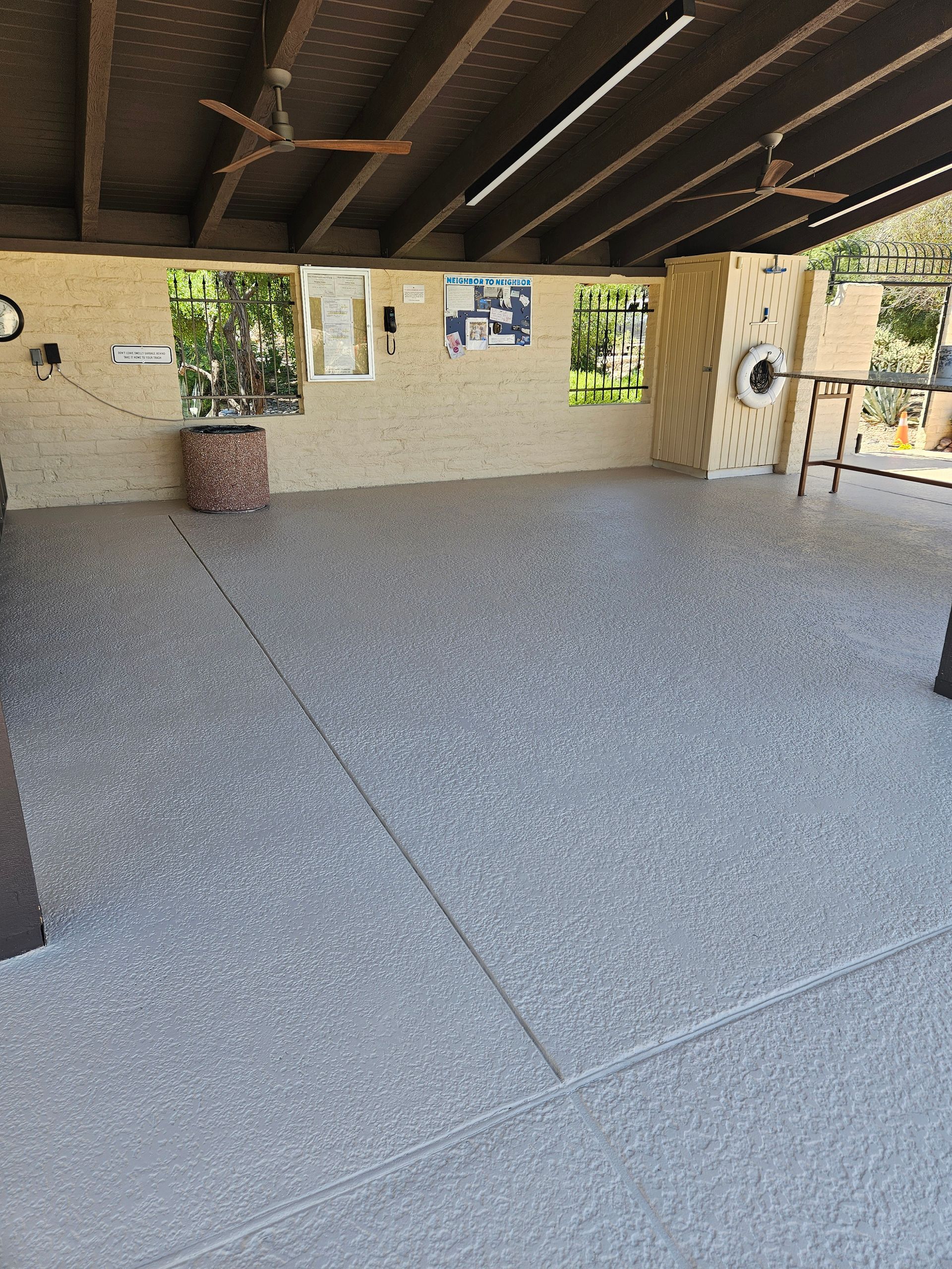 A large room with a concrete floor and a ceiling fan.