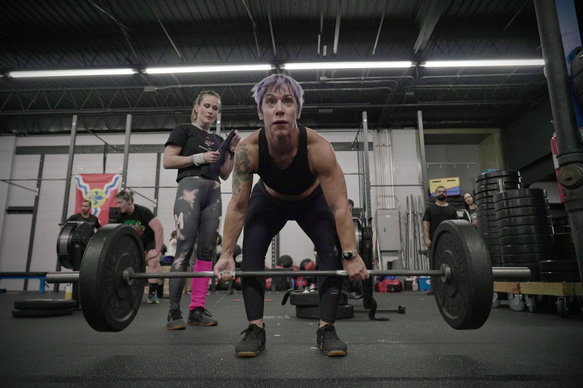 A woman is lifting a barbell in a gym.