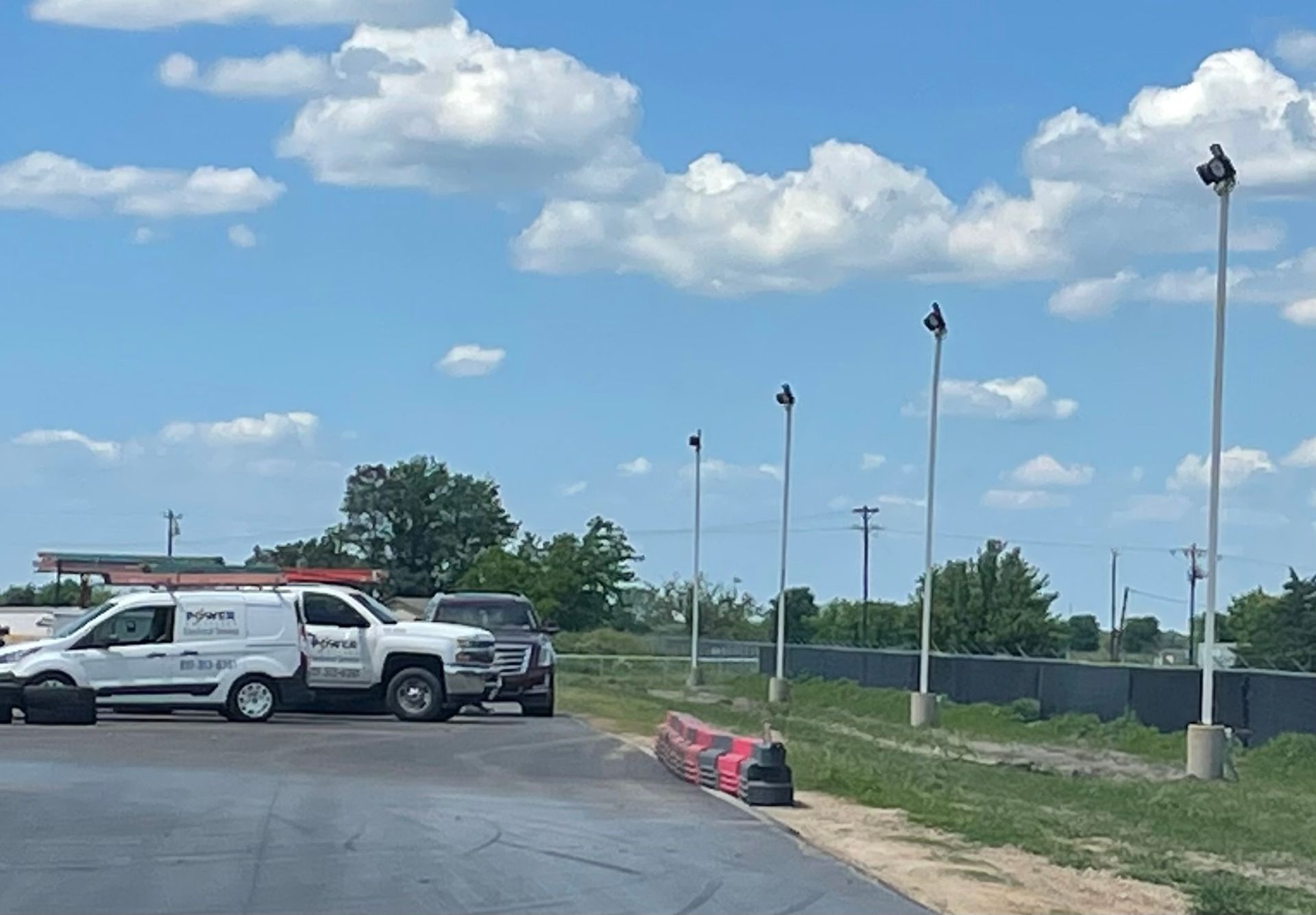 A row of trucks are parked in a parking lot on a sunny day.