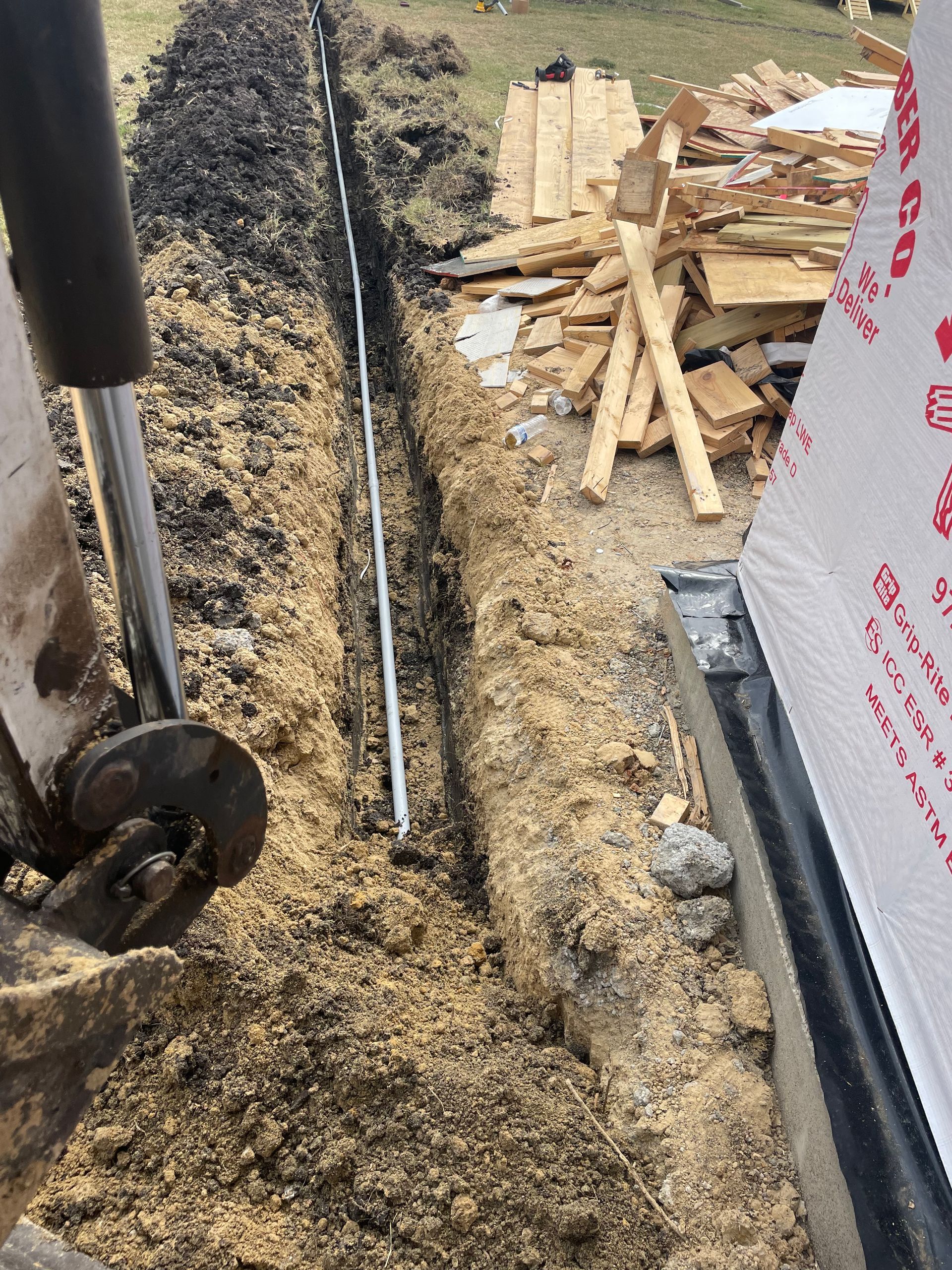 A person is digging a trench in the dirt next to a building.