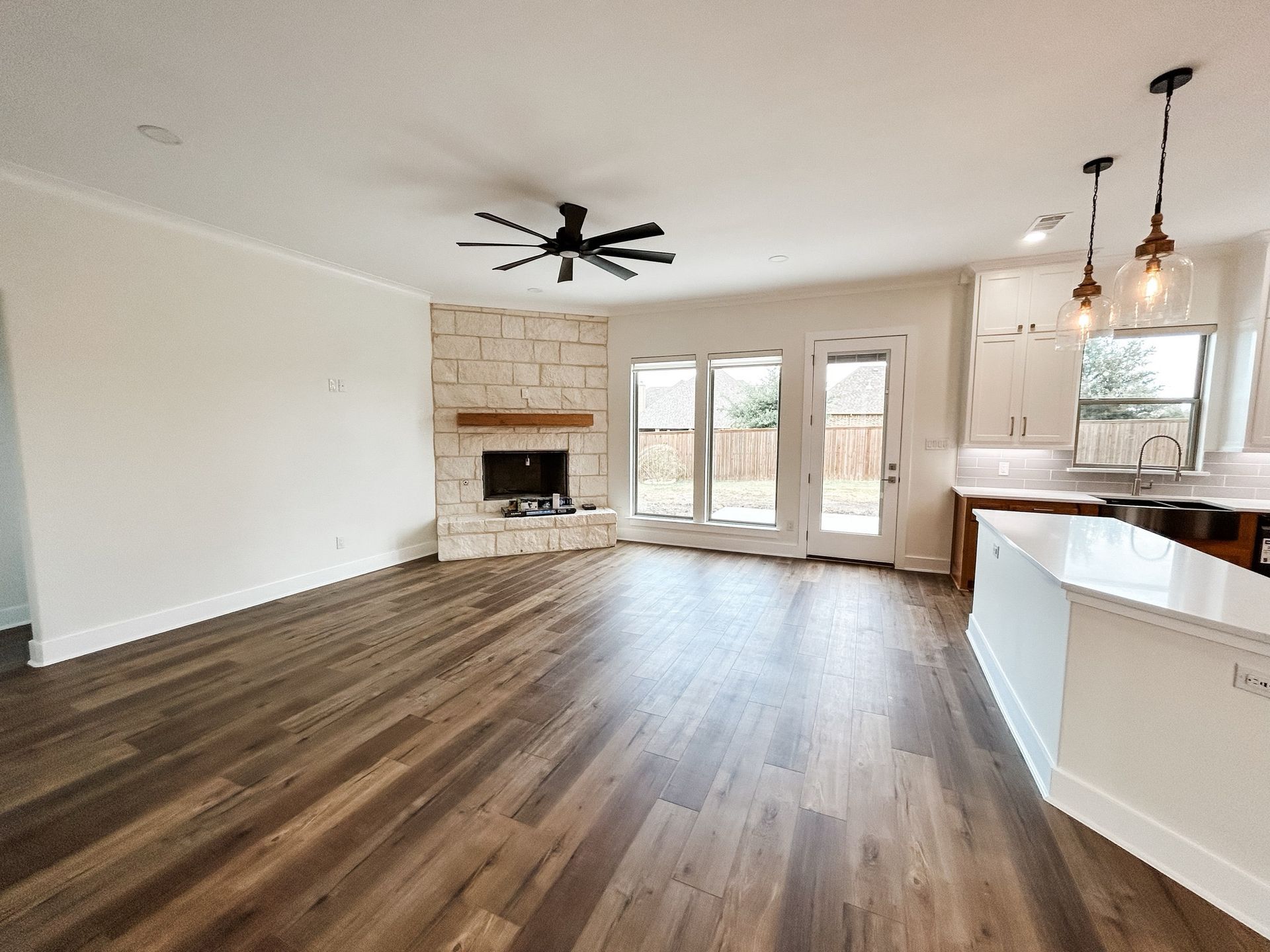 A living room with hardwood floors , a fireplace and a ceiling fan.