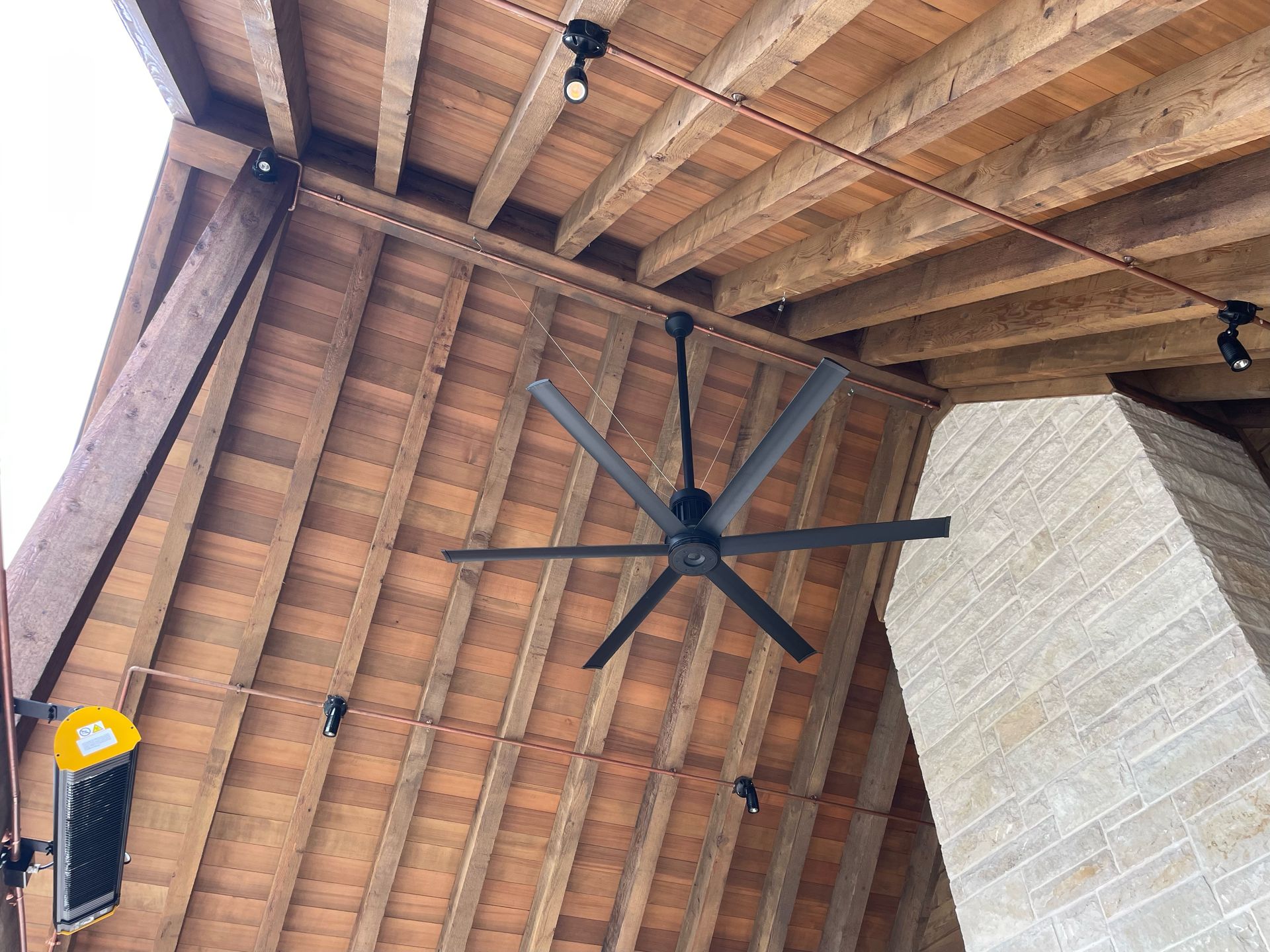 A ceiling fan is hanging from the ceiling of a wooden building.