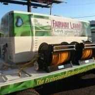 Green Fairway Lawn Care trailer with hose reels parked outdoors